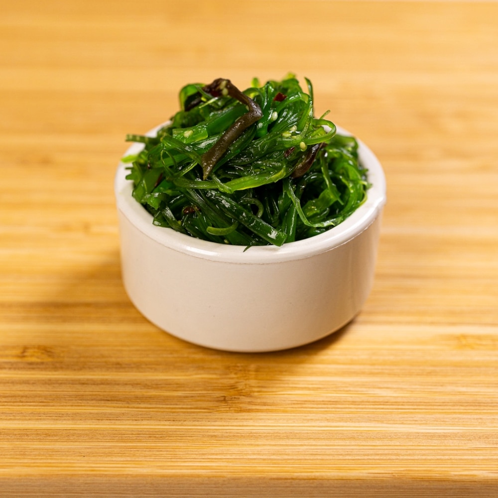 A bowl of seaweed on a wooden table.