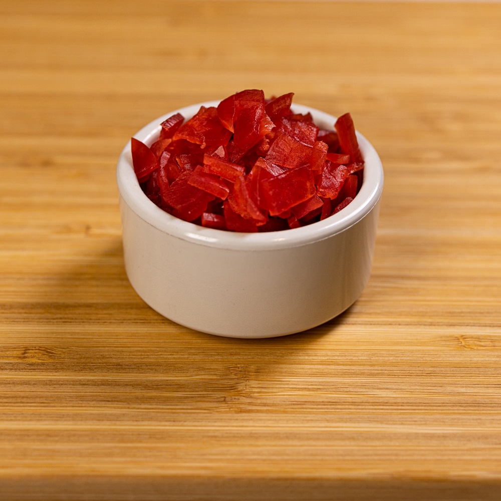 Red goji berries in a white bowl on a wooden table.
