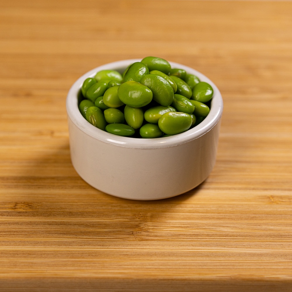 A bowl of green beans on a wooden table.