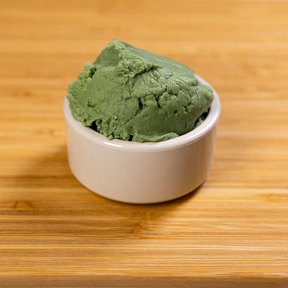A bowl of green ice cream on a wooden table.
