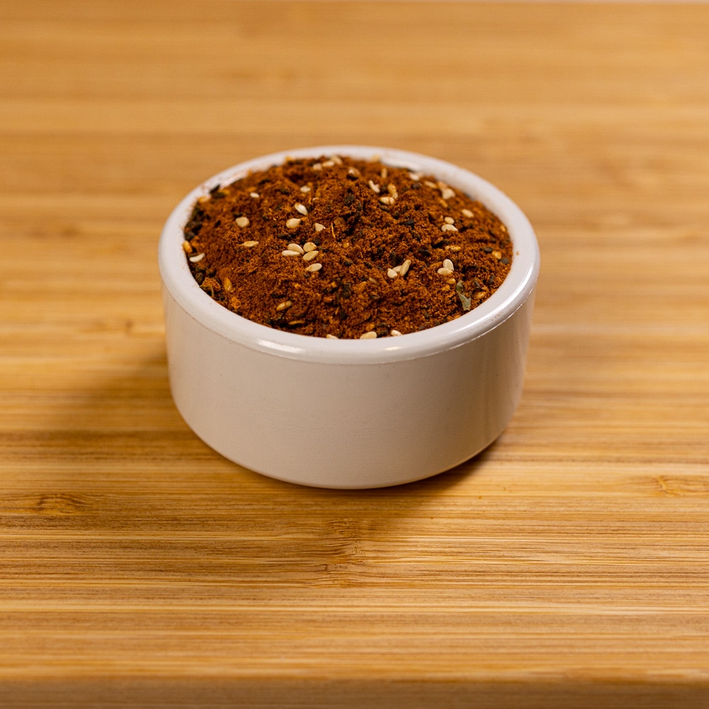 A small bowl of spice on a wooden table.