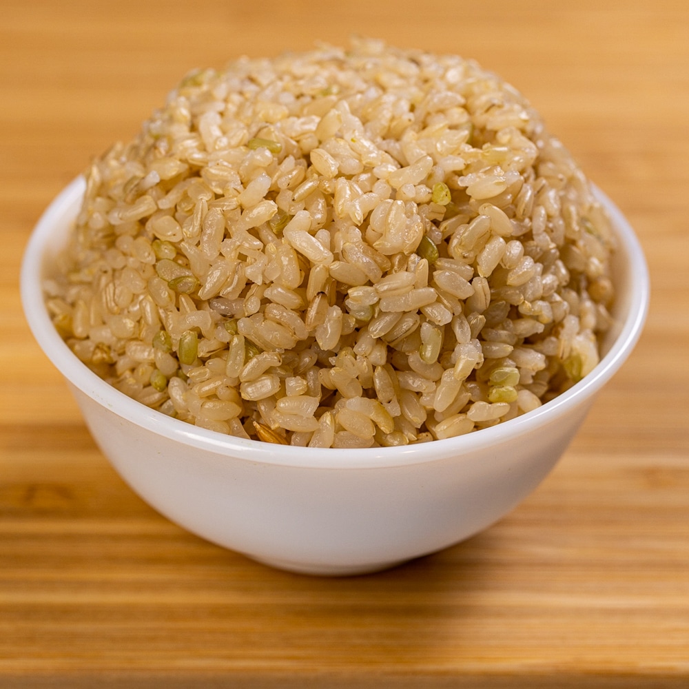 A bowl of brown rice sitting on a wooden table.