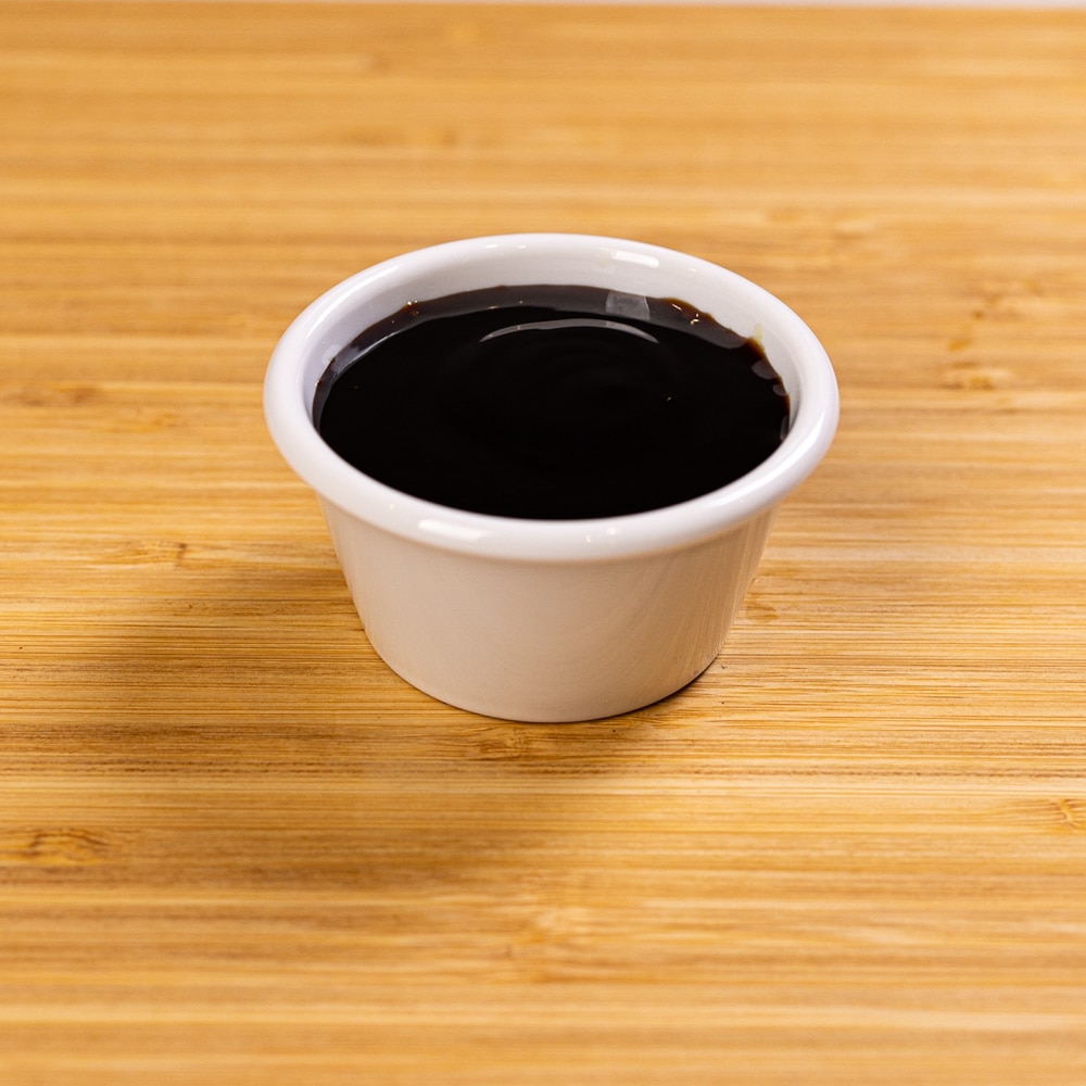 A small bowl of black tea on a wooden table.