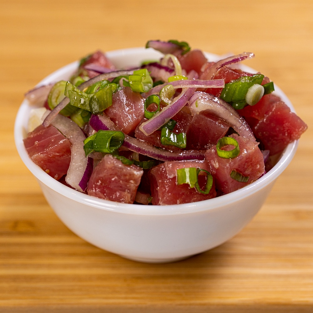 A bowl of tuna salad on a wooden table.