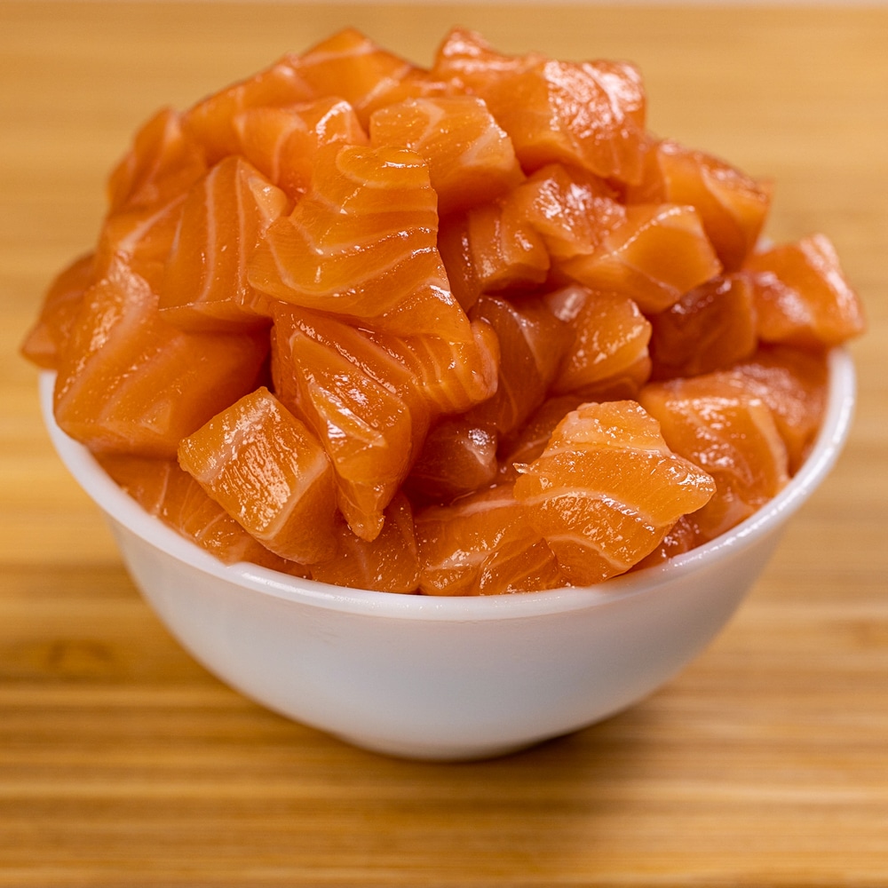Smoked salmon in a white bowl on a wooden table.