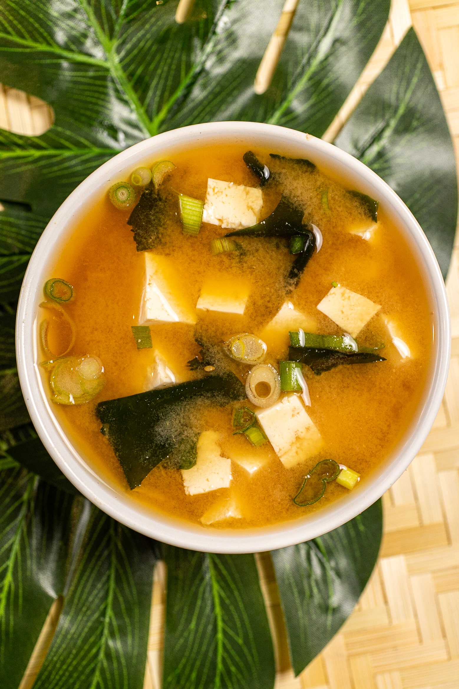 A bowl of tofu soup on a green leaf.