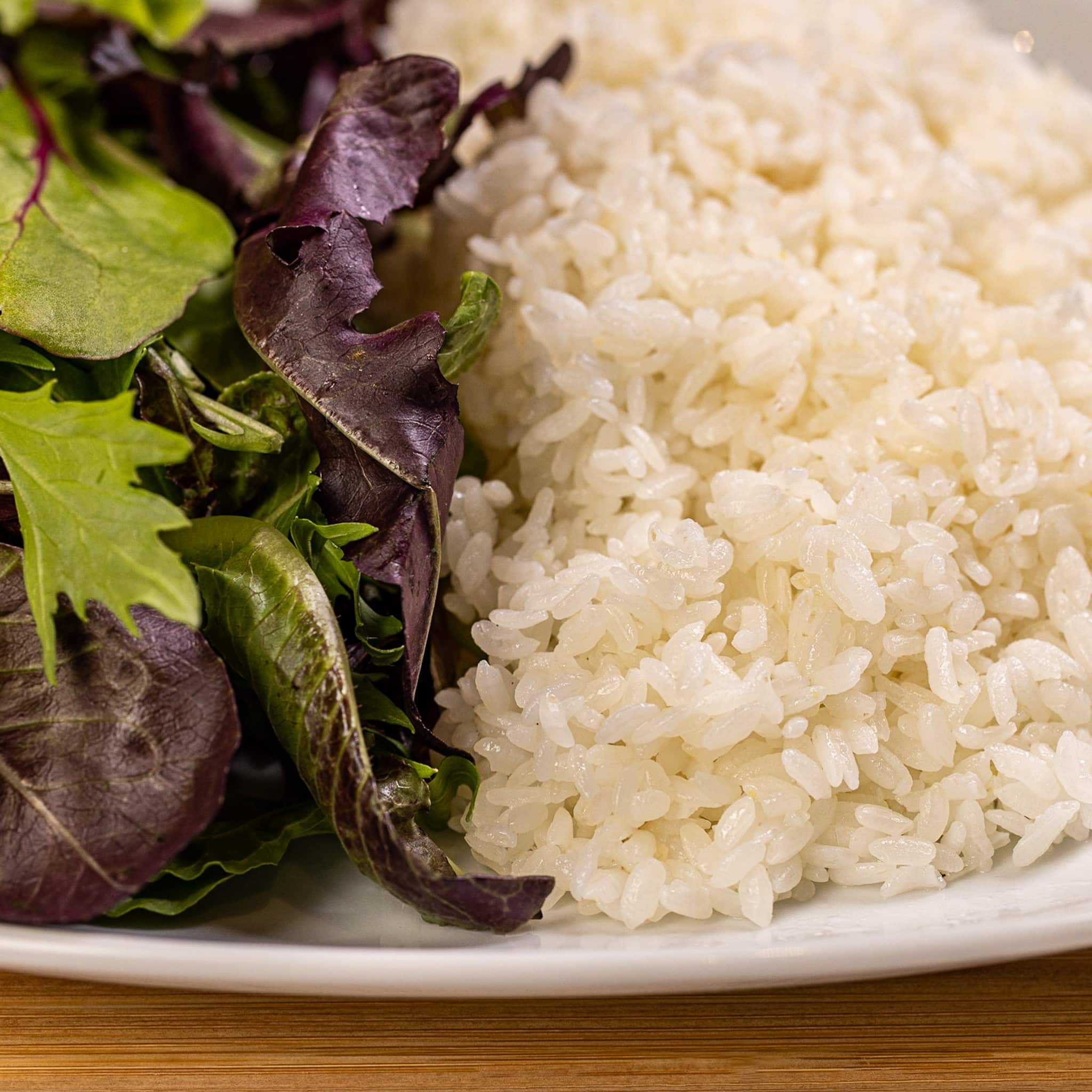 A plate of rice and a salad on a wooden table.